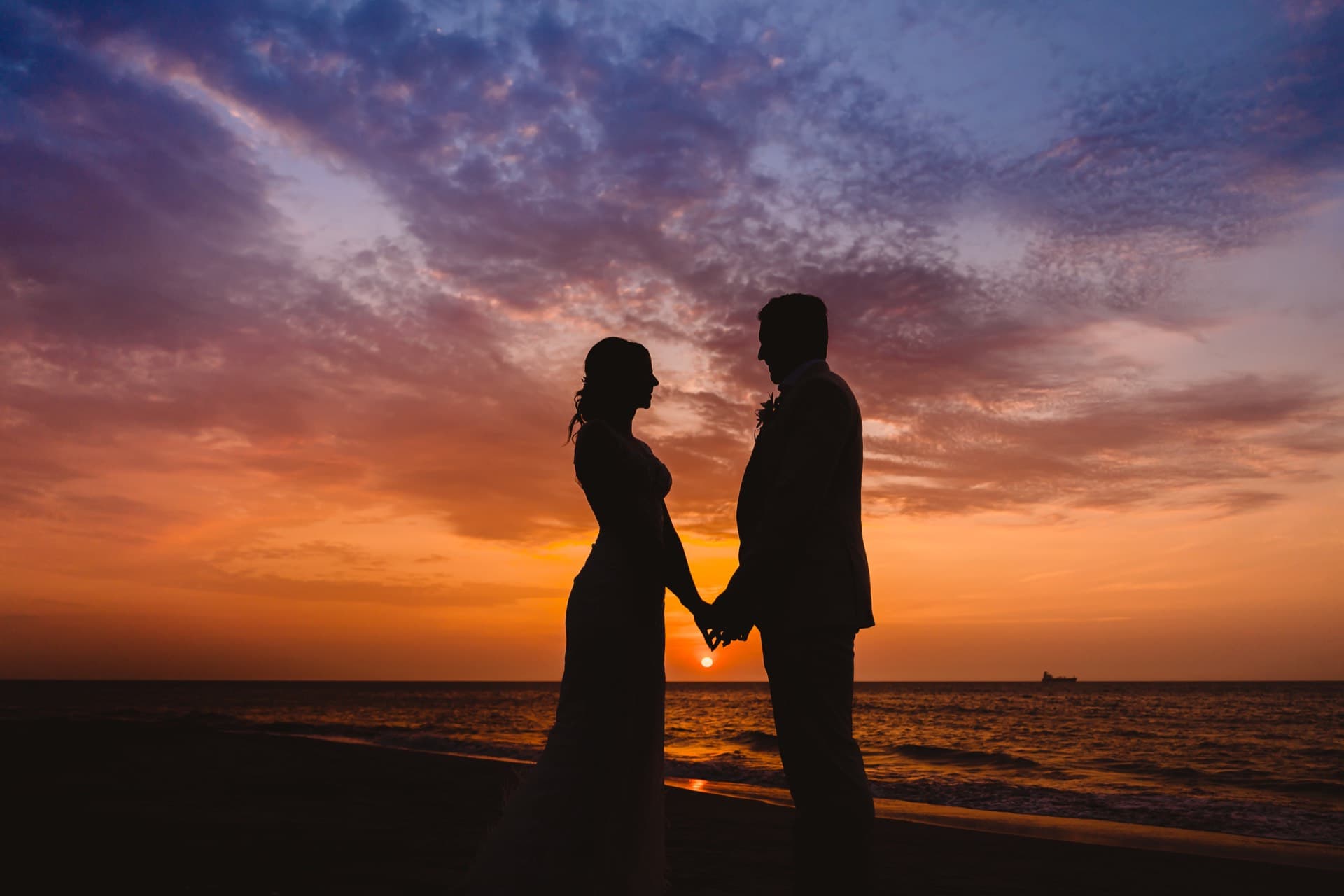 Silueta de una pareja tomándose de la mano en la playa al atardecer